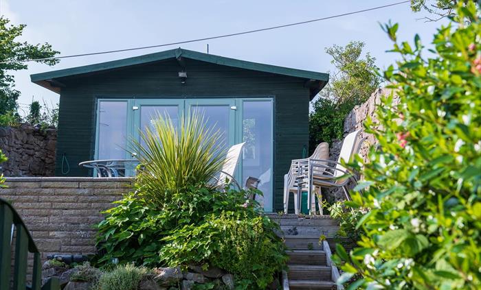 To the rear of the cottage, there is a garden, with a lawn and patio and a summerhouse.  On the patio, there is dining furniture and inside the summer